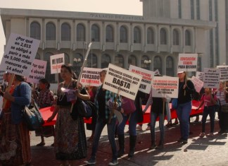 Un grupo de mujeres, con carteles, que visibilizan la violencia sexual contra la mujer, pasa enfrente del Palacio de Justicia