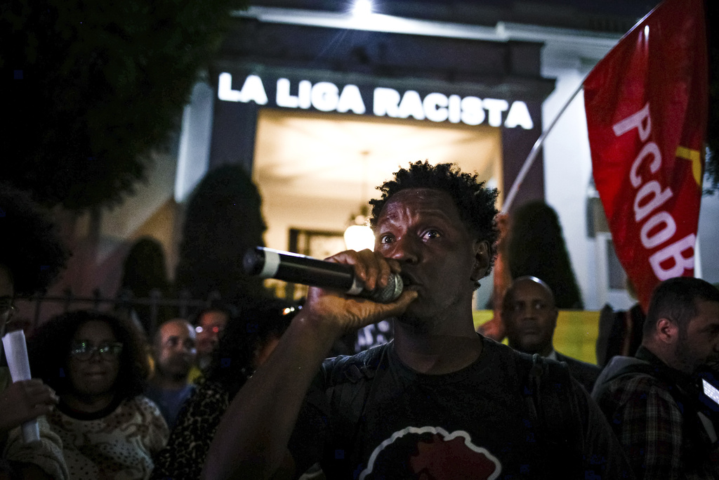 Delante de un mensaje proyectado en la fachada del consulado de España en Sao Paulo, un manifestante habla durante una protesta contra las expresiones racistas lanzadas a Vinícius Júnior, el martes 23 de mayo de 2023 