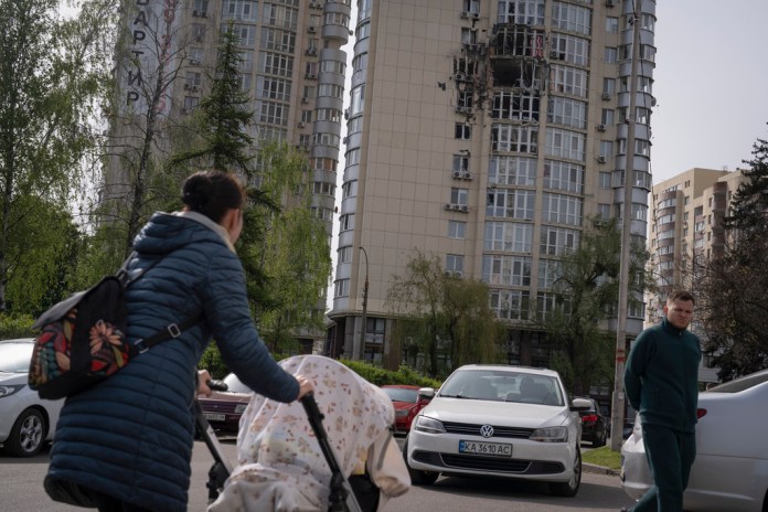 Gente pasa junto a un edificio de apartamentos dañado por restos de un dron derribado durante un ataque ruso la noche anterior en Kiev, Ucrania, el lunes 8 de mayo de 2023.