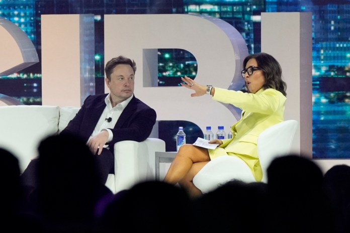 Elon Musk, habla con Linda Yaccarino, presidenta de publicidad en NBC, sobre una conferencia de publicidad, el martes 18 de abril de 2023, en Miami Beach, Florida.