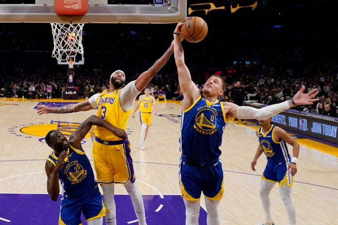 El alero de los Lakers de Los Ángeles Anthony Davis va por el rebote frente a Donte DiVincenzo y Draymond Green de los Warriors de Golden State en el juego 6 de la serie de semifinales de la Conferencia Oeste el viernes 12 de mayo del 2023