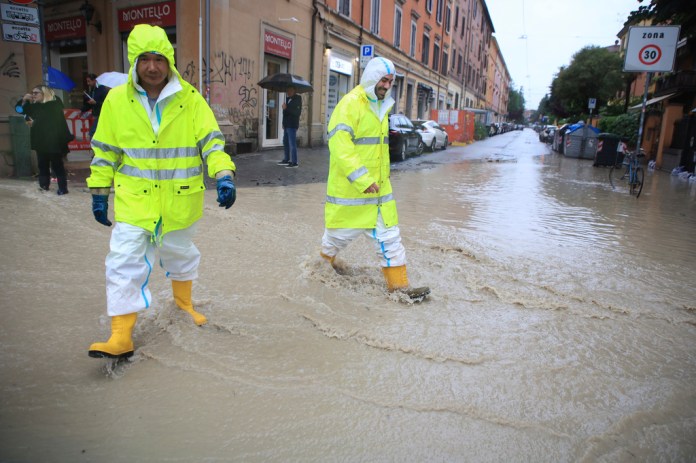 Dos personas cruzan una calle anegada en Bolonia, Italia