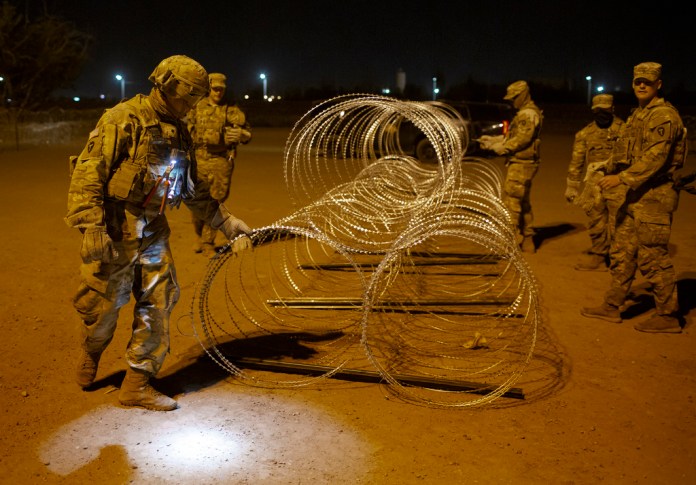 Elementos de la Guardia Nacional de Texas atan hileras de alambre de púas para su instalación cerca de una puerta en el muro fronterizo a primeras horas del jueves 11 de mayo de 2023, en El Paso, Texas. Gran cantidad de migrantes se apresuraban a cruzar la frontera horas antes de que el jueves expiraran las restricciones al asilo relacionadas con la pandemia de COVID-19, ante el temor de que las nuevas medidas les compliquen todavía más ingresar a Estados Unidos. (AP Foto/Andrés Leighton)