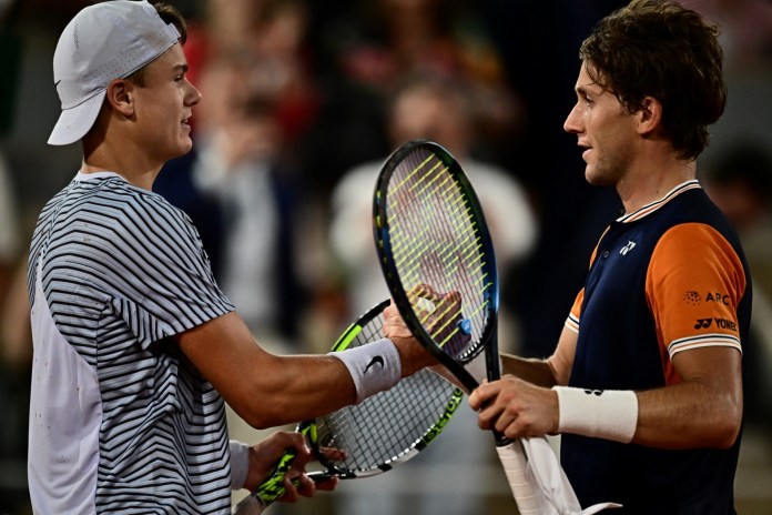 El noruego Casper Ruud (R) le da la mano al danés Holger Rune después de su victoria durante el partido de cuartos de final de singles masculinos el día once del torneo de tenis Roland-Garros