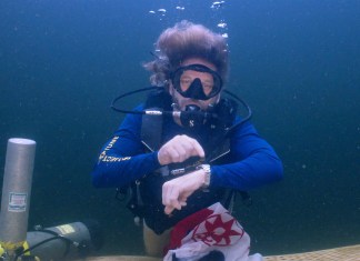 En esta fotografía facilitada por la Oficina de Prensa de los Cayos de Florida, el explorador submarino e investigador médico, doctor Joseph Dituri, señala hacia su reloj.