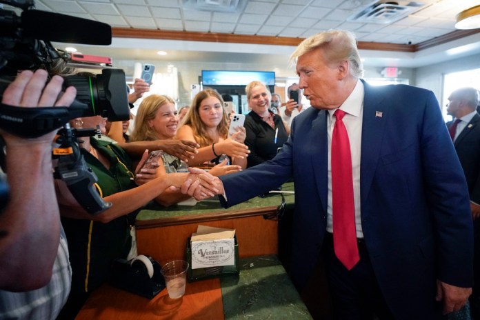 El expresidente Donald Trump saluda a sus seguidores en el restaurante cubano Versailles, en Miami, 