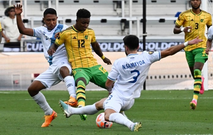 El delantero de Jamaica Demarai Gray (C) compite por el balón con el defensor de Guatemala José Ardón (L) y el defensor de Guatemala José Pinto (D) durante el partido de fútbol de cuartos de final de la Copa Oro