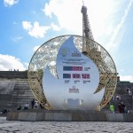 Los peatones pasan frente a un tablero que muestra la cuenta regresiva para el inicio de los Juegos Olímpicos de París 2024 frente a la Torre Eiffel en París, el 26 de julio de 2023. Foto: AFP / Alain Jocard.