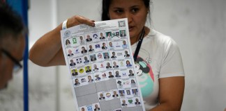 Una trabajadora electoral muestra un voto durante el conteo después del cierre de urnas en las elecciones generales.
