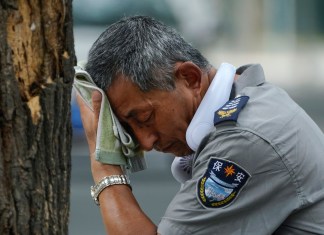 Un guardia de seguridad que lleva un ventilador eléctrico en el cuello se limpia el sudor en un día caluroso en Beijing, el lunes 3 de julio de 2023. Fuertes inundaciones desplazaron a miles de personas en China mientras la capital se tomaba un breve respiro de un calor abrasador.