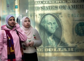 Un grupo de personas frente a un afiche con la imagen de un dólar, en El Cairo, Egipto.