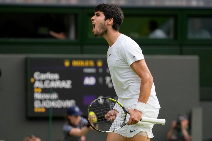 Carlos Alcaraz grita tras ganar un punto ante Novak Djokovic durante la final masculina de Wimbledon en Londres.