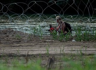 Migrantes caminan entre alambre de púas mientras tratan de cruzar el río Bravo en la frontera de Estados Unidos con México