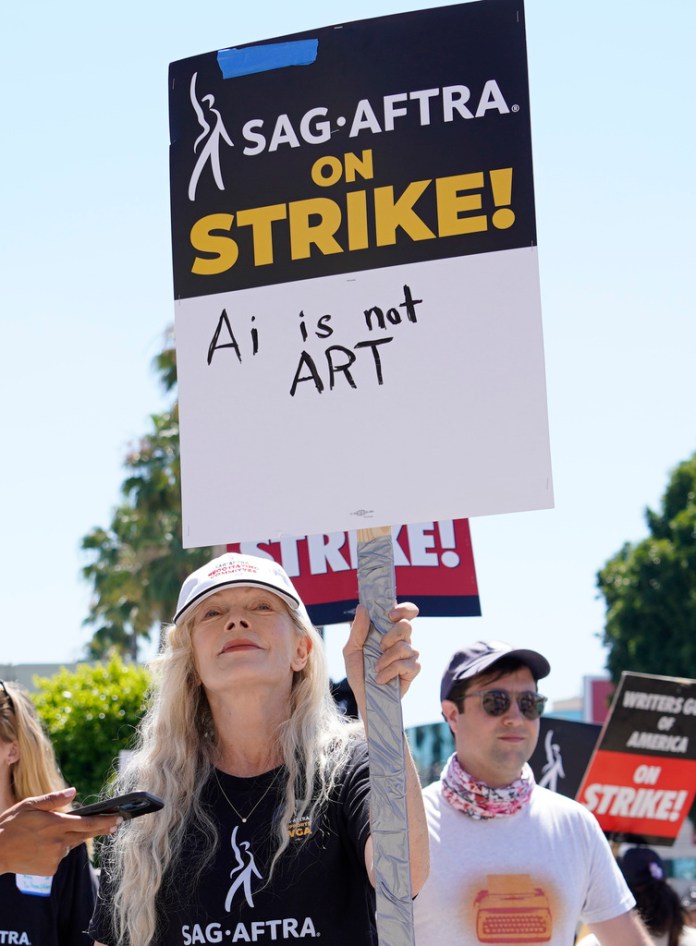 La actriz Frances Fisher sostiene un cartel que dice "IA no es arte" en un mitin de guionistas y actores en huelga fuera de los estudios Paramount en Los Ángeles. 