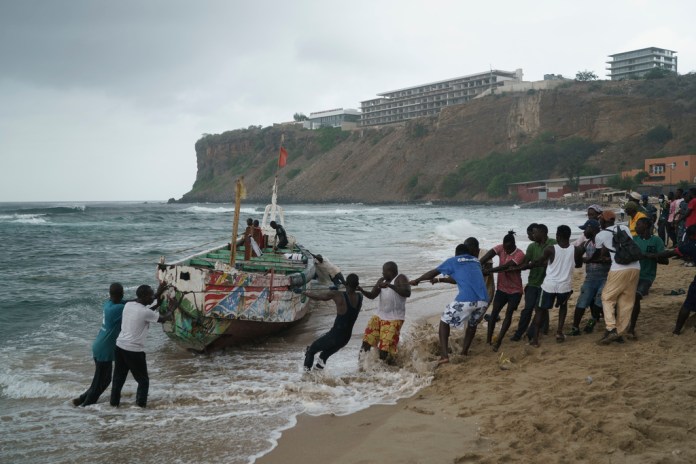 Un grupo de personas ayuda para sacar del mar un bote que, de acuerdo con testigos, naufragó en las costas de Dakar, Senegal, el lunes 24 de julio de 2023.