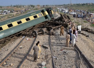 Civiles observan los vagones dañados de u tren de pasajeros que se descarriló cerca de Nawabshah, Pakistán, el domingo 6 de agosto de 2023.