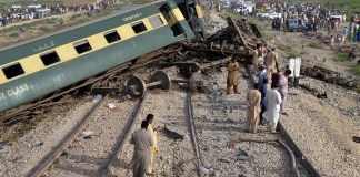 Civiles observan los vagones dañados de u tren de pasajeros que se descarriló cerca de Nawabshah, Pakistán, el domingo 6 de agosto de 2023.