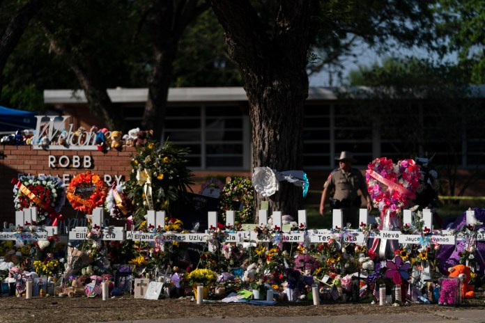 Flores y veladoras colocadas junto a cruces el 28 de mayo de 2022 en un altar instalado afuera de la Escuela Primaria Robb, en Uvalde, Texas, para honrar a las víctimas de una masacre en el colegio.