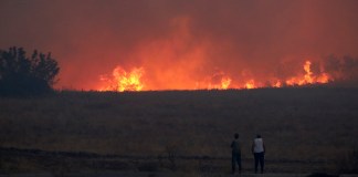 Gente observa un incendio forestal cerca de la ciudad nororiental de Alejandrópolis, Grecia, el domingo 20 de agosto de 2023.