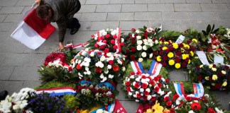 Un hombre con una bandera polaca coloca flores luego de una ceremonia para conmemorar la invasión nazi en Polonia, al inicio de la Segunda Guerra Mundial. Foto La Hora/AP