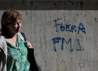 Una mujer pasa junto a un graffiti que dice "Fuera FMI" en español en Buenos Aires el 14 de agosto de 2023, un día después de las elecciones primarias.