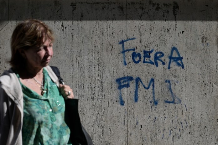 Una mujer pasa junto a un graffiti que dice 