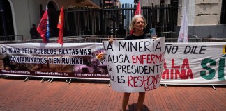 Una mujer sostiene un cartel con un mensaje que dice en español "La minería causa enfermedad, Sr. presidente usted es el responsable" durante una protesta contra un contrato minero que está siendo debatido por la Asamblea Nacional, frente al palacio presidencial en la Ciudad de Panamá.