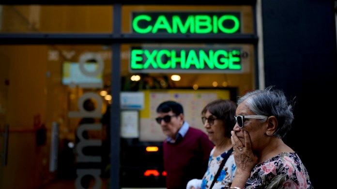 Las personas caminan frente a una casa de cambio en Buenos Aires, Argentina. Foto La Hora/AP