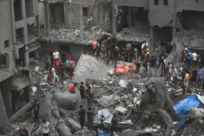 Palestinos inspeccionan los daños en edificios destruidos por ataques aéreos israelíes. Foto La Hora/AP