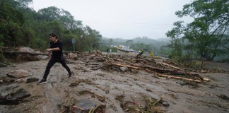 Un hombre cruza una carretera bloqueada por un deslizamiento de tierra causado por el huracán Otis