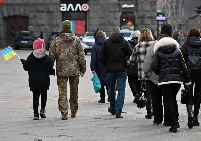 Una niña lleva una bandera ucraniana mientras camina con su padre, un militar ucraniano, en el centro de Kiev el 9 de noviembre de 2023, en medio de la invasión rusa en Ucrania.