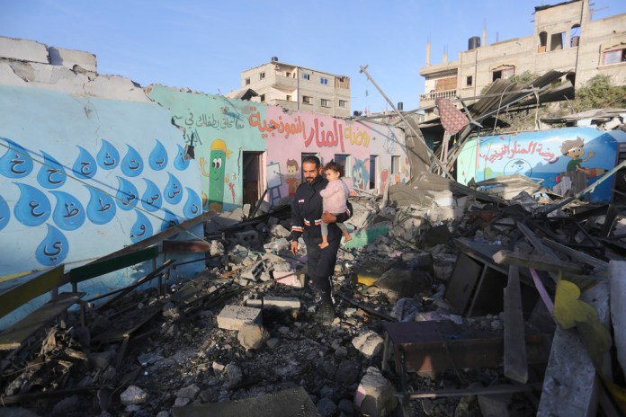 Palestinos pasan junto a un edificio destruido por un bombardeo nocturno israelí, en Rafah, en la Franja de Gaza.
