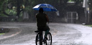 Un hombre anda en bicicleta bajo la lluvia durante la alerta roja decretada por el gobierno