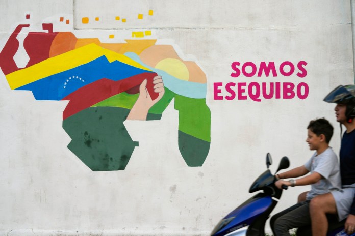 Un niño conduce una motocicleta por delante de un mural con el mapa de Venezuela, que incluye el territorio de Esequibo. Foto La Hora/AP