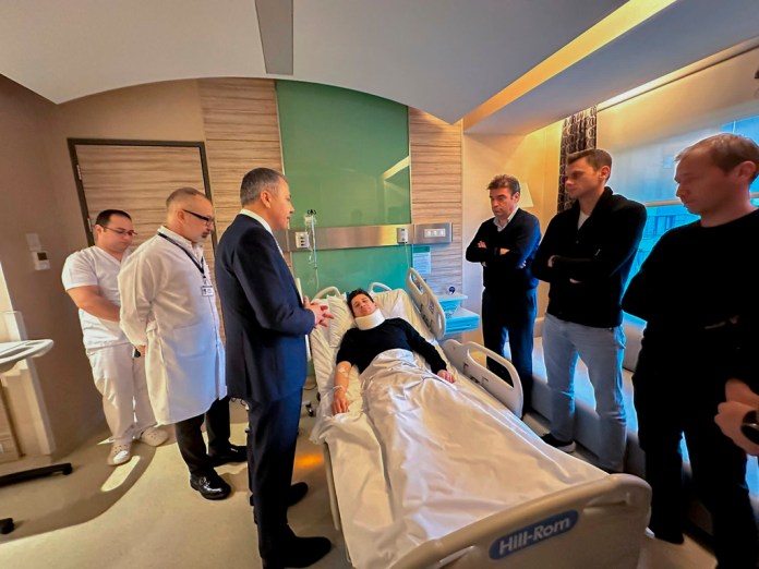 En esta imagen distribuida por el Ministerio del Interior, el árbitro turco Halil Umut Meler (centro), descansa en una cama mientras habla con el ministro del Interior, Ali Yerlikaya (tercero por la izquierda), en el hospital Acibadem, en Ankara, el 12 de diciembre de 2023.