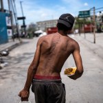 Nicolás Gonzáles camina con un plato de comida a la salida de la Casa Comunitaria. Foto La Hora/AP