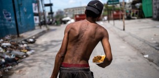 Nicolás Gonzáles camina con un plato de comida a la salida de la Casa Comunitaria. Foto La Hora/AP
