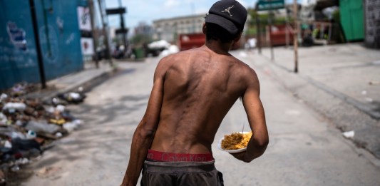 Nicolás Gonzáles camina con un plato de comida a la salida de la Casa Comunitaria. Foto La Hora/AP