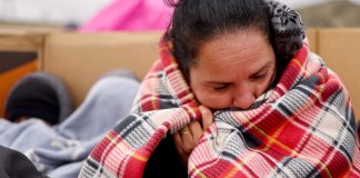 Un migrante ecuatoriano solicitante de asilo intenta mantenerse abrigado con una manta donada en un campamento improvisado poco después de cruzar la frontera, mientras espera ser procesado por la Patrulla Fronteriza de EE. UU., el 30 de noviembre de 2023 en Jacumba.