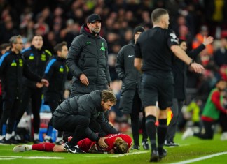 Kostas Tsimikas del Liverpool se queja del dolor tras una tacleada de Bukayo Saka del Arsenal y golpearse contra el técnico Jürgen Klopp en el encuentro de la Liga Premier el sábado 23 de diciembre del 2023. (AP Foto/Jon Super)