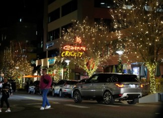 Dos personas cruzan una avenida en el distrito comercial Cherry Creek North el viernes 15 de diciembre de 2023, en Denver. (AP Foto/David Zalubowski)
