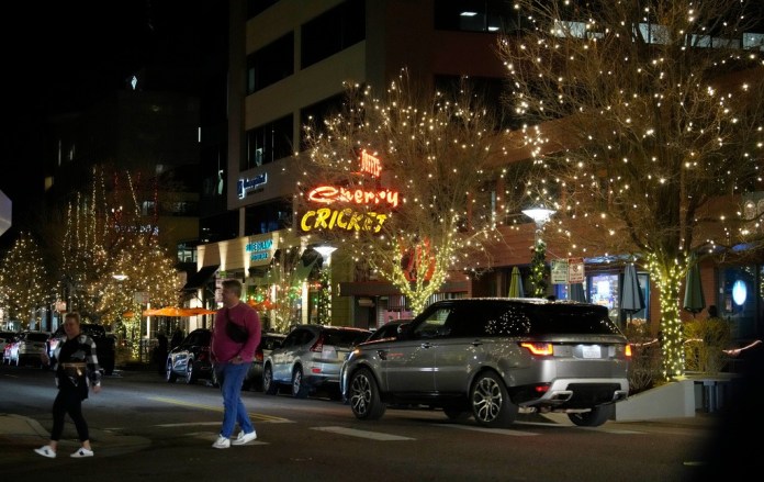Dos personas cruzan una avenida en el distrito comercial Cherry Creek North el viernes 15 de diciembre de 2023, en Denver. (AP Foto/David Zalubowski)