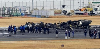 Policías y bomberos se reúnen alrededor de los restos calcinados de un avión de la guardia costera japonesa en el aeropuerto de Haneda, el 3 de enero de 2024, en Tokio,