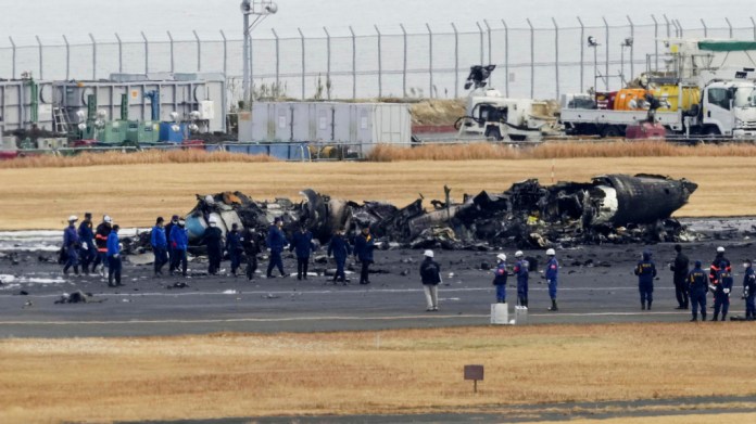 Policías y bomberos se reúnen alrededor de los restos calcinados de un avión de la guardia costera japonesa en el aeropuerto de Haneda, el 3 de enero de 2024, en Tokio,