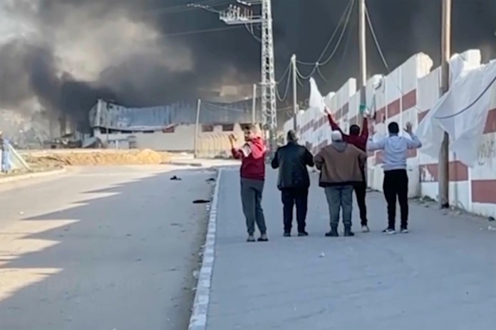Esta imagen tomada de un video de ITV News muestra a un grupo de cinco hombres que caminan por una calle al oeste de la ciudad meridional de Jan Yunis, en Gaza, mientras levantan las manos y uno ondea una bandera blanca. El ejército israelí ha anunciado que revisará el disparo mortal a uno de los hombres. (ITV News via AP)