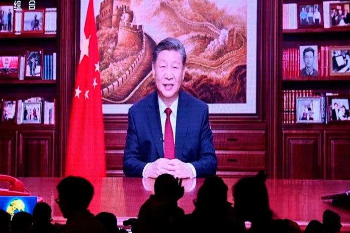 La gente cena en un restaurante mientras una pantalla transmite al presidente de China, Xi Jinping, mientras pronuncia su discurso de Año Nuevo en Beijing el 31 de diciembre de 2023.