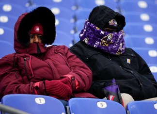 Dos personas de cobijan del frío en el partido de fútbol americano entre los Ravens de Baltimore y los Texans de Houston, en Baltimore, el 20 de enero de 2024. (Foto AP/Matt Slocum)