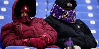 Dos personas de cobijan del frío en el partido de fútbol americano entre los Ravens de Baltimore y los Texans de Houston, en Baltimore, el 20 de enero de 2024. (Foto AP/Matt Slocum)