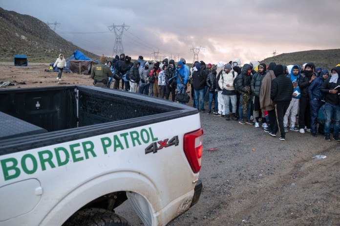 Solicitantes de asilo esperan en fila para ser procesados ​​por la Patrulla Fronteriza en un campamento improvisado cerca de la frontera entre Estados Unidos y México al este de Jacumba, condado de San Diego, California, el 2 de enero de 2024