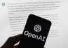 El logotipo de OpenAI se ve en un teléfono celular frente a una pantalla de computadora que muestra un resultado de ChatGPT. Foto La Hora: ChatGPT